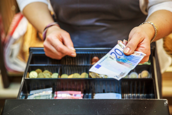 Cashier at a till holding euro currency notes