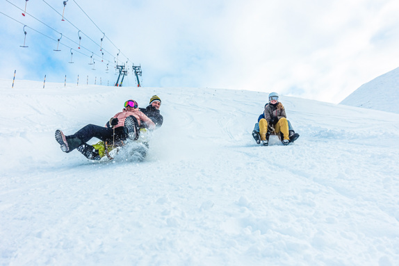 Friends sledding down a snowy mountain