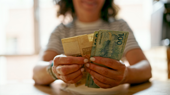 woman counting brazil real banknotes at home