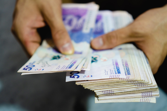 Hands holding Colombian peso currency notes
