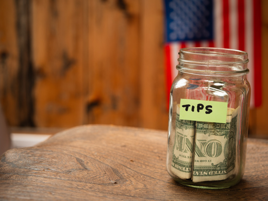 Tip jar with US dollars and American flag background
