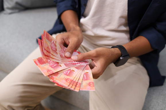 male hands holding rupiah banknotes