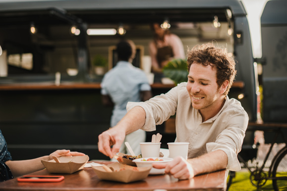 Man eating food next to a street food truck